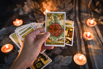Hand holding tarot card with candlelight on the darkness background for Astrology Occult Magic illustration - Magic Spiritual Horoscopes and Palm reading fortune teller concept - 319444116