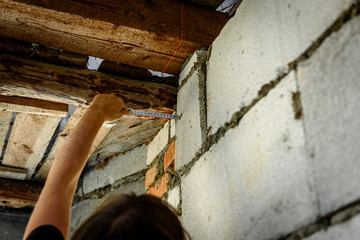 Worker with roulette measuring tape drawing marks on wall.