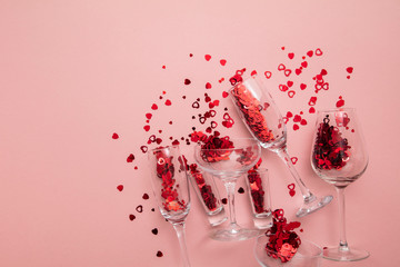 Valentine's day date night background. Drinks glasses with red heart confetti.