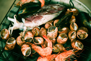 shellfish grilled seafood on stove - crab  prawns shrimps squid mussels cooked burn on grill barbecue holiday party on the beach