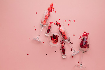 Valentine's day date night background. Drinks glasses with red heart confetti.