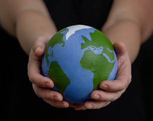 Close up woman holds planet in hands. Ecology concept. Isolated on dark background