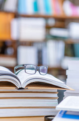 Eyeglasses lies on open book in a library. Empty space for text