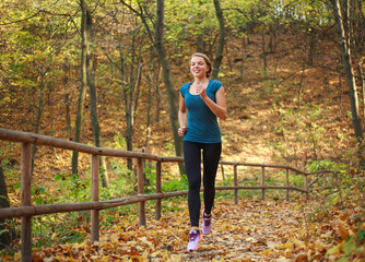 Young slender woman runs in forest park, healthy lifestyle outdoors in nature