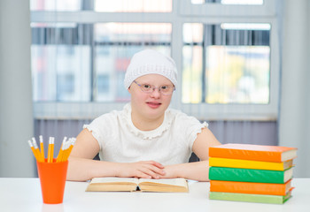 Smiling young girl with Down Syndrome reads book at home