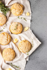 Cheese scones, pieces of cheese and thyme on a grey napkin. Grey stone background, toned image.
