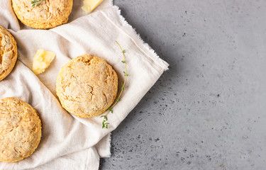 Cheese scones, pieces of cheese and thyme on a grey napkin. Grey stone background, toned image.