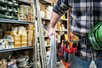 Electrician in the electrical parts store is holding the roll of electrical cable. Construction industry, electrical system.