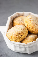 Canvas bag with homemade scone with cheese, thyme and pieces of cheese. Freshly baked delicious English scones. Grey stone background.