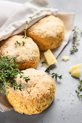 Canvas bag with homemade scone with cheese, thyme and pieces of cheese. Freshly baked delicious English scones. Grey stone background.