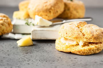 Wooden cutting board with delicious English scones with cheese. Perfect breakfast or lunch. Grey stone background.