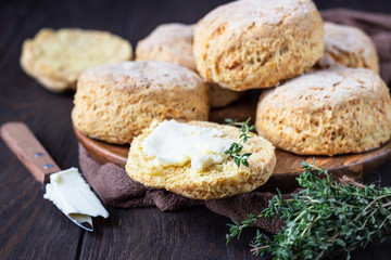 Wooden plate with English scones or buttermilk biscuits with cheese and thyme, dark brown wooden...