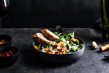 Gordijnen Buckwheat salad with lamb's lettuce, pomegranat seeds, goat cheese, mandarine and spring onion, Served with whole grain baguette and red wine. Black table and black background. © mateuszsiuta