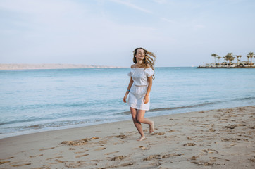 Fototapeta na wymiar Happy woman enjoying beach running joyful in summer by tropical blue water