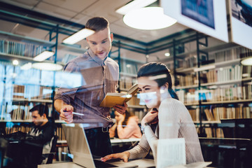 Concentrated students doing research and using laptop together in library