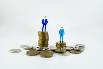Miniature people: small businessmen standing on stack of coins with some coins laying in front of them on a white backround. Money, Financial, Business Growth concept.