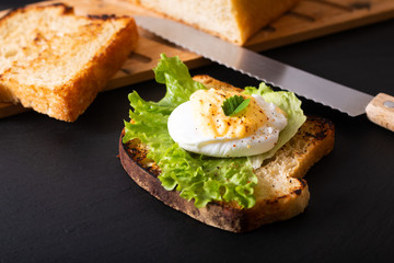 Organic Food breakfast concept homemade Poached egg or eggs benedict on sourdough bread toasted on black slate board