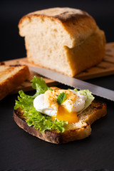 Organic Food breakfast concept homemade Poached egg or eggs benedict on sourdough bread toasted on black slate board