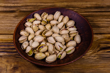 Ceramic plate with pistachio nuts on a wooden table