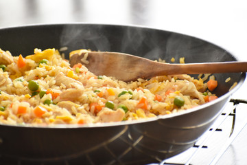 Chicken and egg fried rice with green peas and carrot in a frying pan. 