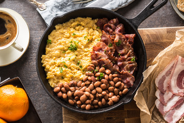 Full table of english breakfast. Scrambled eggs grilled bacon beans toast bread orange juice and coffee