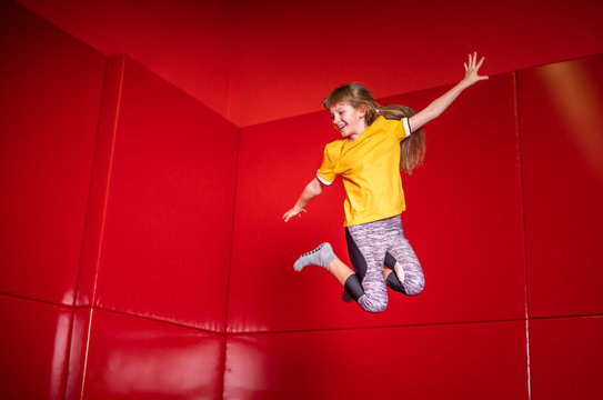 Child having fun while jumping on trampoline in fitness center