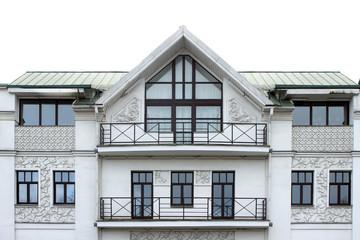 facade of a light-gray well-groomed plastered building with stucco in the form of grape leaves and circles, weaves, with ornament. Facade of a house with windows and balconies, triangular roof