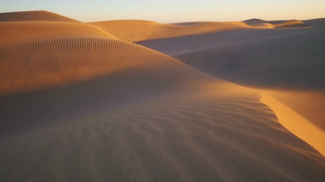 walking in sandy beautiful desert at sunrise along the dunes in slow motion, dunes of Maspalomas, Gran Canaria, Canary Islands