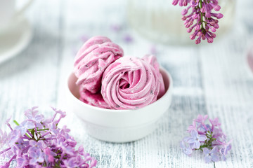 Fototapeta na wymiar Lilac and homemade pink marshmallow in white ceramic bowl. Romantic spring morning. Selective focus
