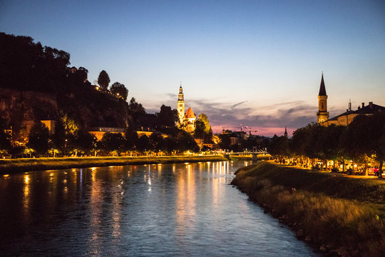 Saltzburg, Austria at night overlooking the Salzach river with lights reflecting on the water