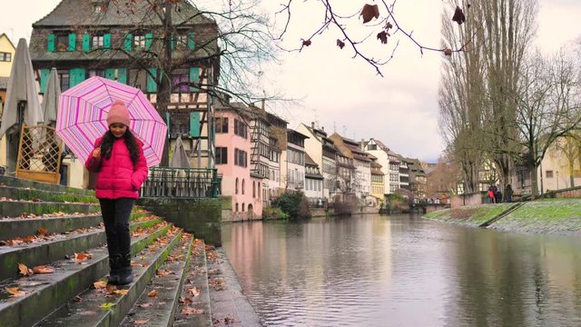 Ni&ntilde;a con paraguas rosa camina hacia delante en escalinata de canal de Estrasburgo