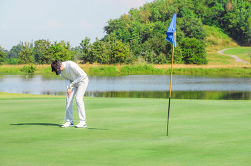 Sport Healthy. Golfer asian sporty woman focus putting golf ball aim on outdoor the green golf on sunset evening relax time. Healthy and Lifestyle Concept