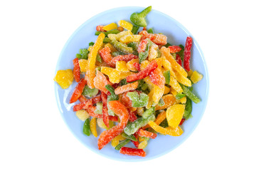 Colorful chopped and frosted peppers on plate. Top view on frozen vegetables.