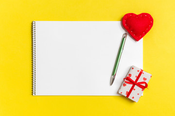 Top view of craft notebook surrounded with hearts and gift boxes on colorful background. Valentine's day