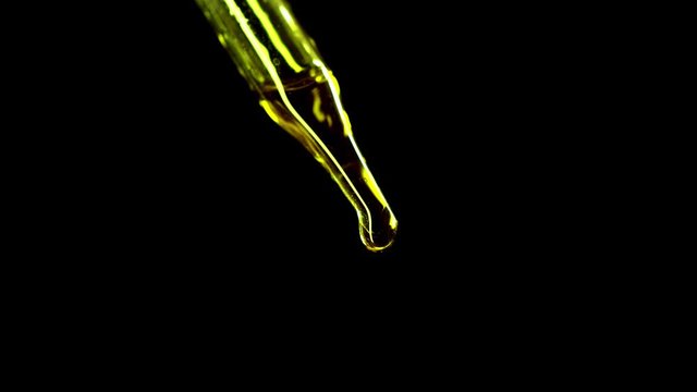CBD oil ends with air bubbles in a dropper from a medical drop of marijuana on a black background