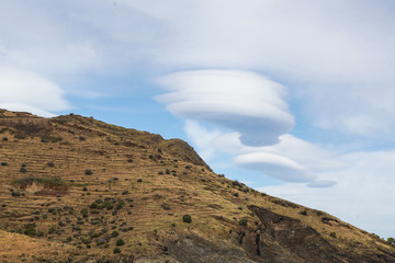 Round unusual clouds on blue sky over mountain and sea
