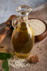 Obraz na płótnie Canvas Healthy Sesame oil in glass bottle and sesame seeds on wooden background Vertical
