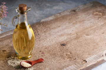 Sesame oil in glass bottle and sesame seeds on wooden background Copy space Rustic
