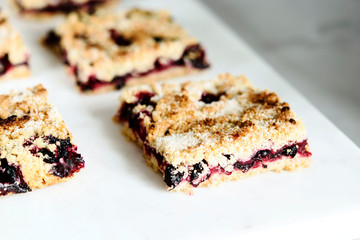 Honeysuckle crumble cake sliced into pieces on grey marble tray. Homemade streusel berries pie.  Selective focus