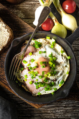 Fried eggs with ham on an old wooden background.