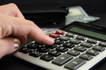 hand counts income with a calculator on the background of dollars. Close-up