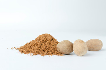 Nutmeg powder and whole nutmegs on the white background