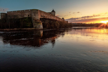 Fototapeta na wymiar View of a medieval fortress and a river at sunrise