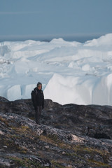 Greenland tourist man explorer overlooking Icefjord in Ilulissat. Travel in arctic landscape nature...