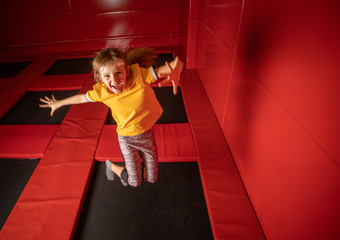 Little girl jumping on trampoline in fly park - obrazy, fototapety, plakaty