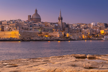 Fototapeta na wymiar Rocky coastline of Malta and beautiful architecture of the Valletta city at dawn