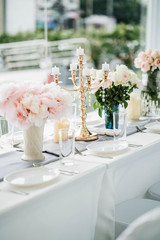 White long set wedding dinner table with decoration, candlestick, glasses, and flowers. Selective focus.