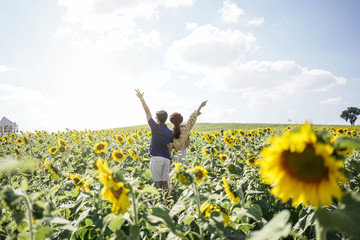 A young couple among Beautiful Landscape of sunflowers blooming in the field with mountain range horizon  background with sunlight.