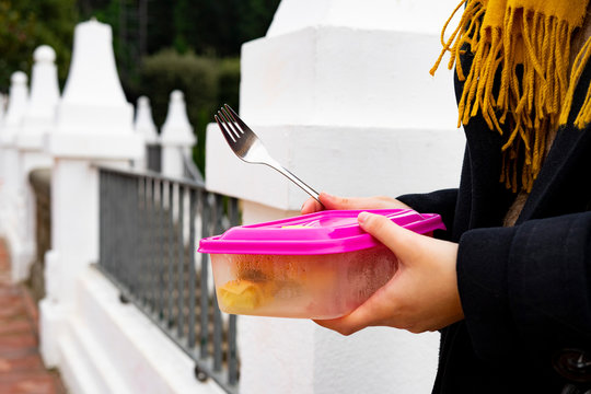 Young woman with a food tupper on the street.