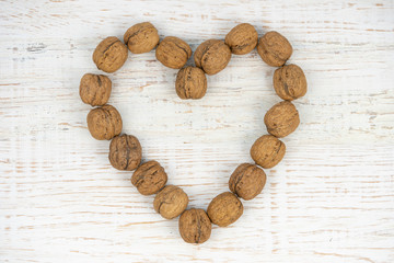 Nuts placed on a heart shape on a white wooden table